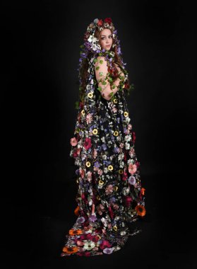 Kelt Bahar Tanrıçası Olarak Kadın Modeli 'nin Portresi Beltane Pagan Mitolojisinden esinlenerek Çiçek Fantezi Pelerini Kostümü. Uzaklaşmak, geriye doğru poz vermek, Karanlık Stüdyo Arkaplanı 'nda soyutlanmak