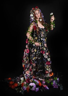 Kelt Bahar Tanrıçası Olarak Kadın Modeli 'nin Portresi Beltane Pagan Mitolojisinden esinlenerek Çiçek Fantezi Pelerini Kostümü. Uzaklaşmak, geriye doğru poz vermek, Karanlık Stüdyo Arkaplanı 'nda soyutlanmak