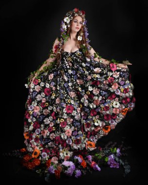 Kelt Bahar Tanrıçası Olarak Kadın Modeli 'nin Portresi Beltane Pagan Mitolojisinden esinlenerek Çiçek Fantezi Pelerini Kostümü. Uzaklaşmak, geriye doğru poz vermek, Karanlık Stüdyo Arkaplanı 'nda soyutlanmak