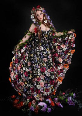 Kelt Bahar Tanrıçası Olarak Kadın Modeli 'nin Portresi Beltane Pagan Mitolojisinden esinlenerek Çiçek Fantezi Pelerini Kostümü. Uzaklaşmak, geriye doğru poz vermek, Karanlık Stüdyo Arkaplanı 'nda soyutlanmak