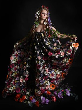 Kelt Bahar Tanrıçası Olarak Kadın Modeli 'nin Portresi Beltane Pagan Mitolojisinden esinlenerek Çiçek Fantezi Pelerini Kostümü. Uzaklaşmak, geriye doğru poz vermek, Karanlık Stüdyo Arkaplanı 'nda soyutlanmak
