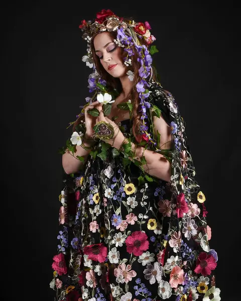 Kelt Bahar Tanrıçası Olarak Güzel Kadın Modeli Portreleri, Beltane Pagan Mitolojisinden esinlenerek Çiçek Fantezi Pelerini Kostümü. izole Karanlık Stüdyo Arkaplanı