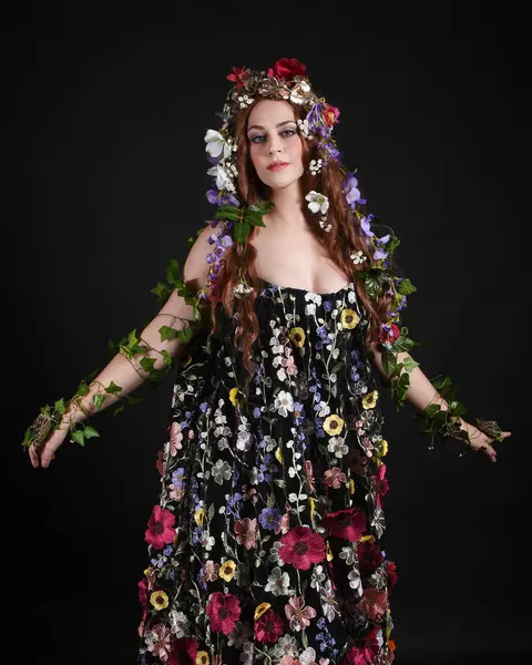 Kelt Bahar Tanrıçası Olarak Güzel Kadın Modeli Portreleri, Beltane Pagan Mitolojisinden esinlenerek Çiçek Fantezi Pelerini Kostümü. izole Karanlık Stüdyo Arkaplanı