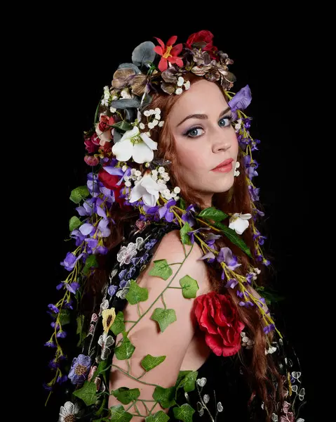 Kelt Bahar Tanrıçası Olarak Güzel Kadın Modeli Portreleri, Beltane Pagan Mitolojisinden esinlenerek Çiçek Fantezi Pelerini Kostümü. izole Karanlık Stüdyo Arkaplanı