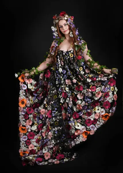 Kelt Bahar Tanrıçası Olarak Kadın Modeli 'nin Portresi Beltane Pagan Mitolojisinden esinlenerek Çiçek Fantezi Pelerini Kostümü. Uzaklaşmak, geriye doğru poz vermek, Karanlık Stüdyo Arkaplanı 'nda soyutlanmak