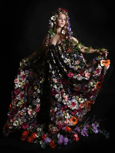 Kelt Bahar Tanrıçası Olarak Kadın Modeli 'nin Portresi Beltane Pagan Mitolojisinden esinlenerek Çiçek Fantezi Pelerini Kostümü. Uzaklaşmak, geriye doğru poz vermek, Karanlık Stüdyo Arkaplanı 'nda soyutlanmak