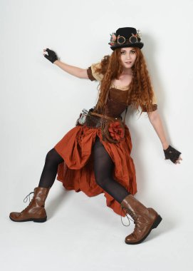 Uzun, yürüyen Steampunk Botanikçisi, çılgın bilim adamı, silindir şapkalı ve gözlüklü kadın model. Kızıl Saçlı Fantezi Karakteri Beyaz Stüdyo Arkaplanında Pozisyon