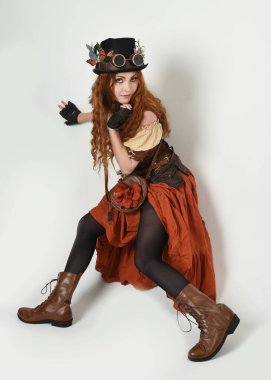 Uzun, yürüyen Steampunk Botanikçisi, çılgın bilim adamı, silindir şapkalı ve gözlüklü kadın model. Kızıl Saçlı Fantezi Karakteri Beyaz Stüdyo Arkaplanında Pozisyon