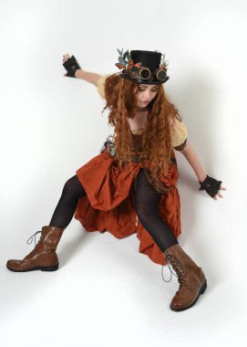 Uzun, yürüyen Steampunk Botanikçisi, çılgın bilim adamı, silindir şapkalı ve gözlüklü kadın model. Kızıl Saçlı Fantezi Karakteri Beyaz Stüdyo Arkaplanında Pozisyon