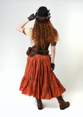 Uzun, yürüyen Steampunk Botanikçisi, çılgın bilim adamı, silindir şapkalı ve gözlüklü kadın model. Kızıl Saçlı Fantezi Karakteri Beyaz Stüdyo Arkaplanında Pozisyon