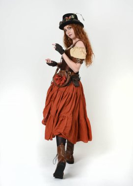 Uzun, yürüyen Steampunk Botanikçisi, çılgın bilim adamı, silindir şapkalı ve gözlüklü kadın model. Kızıl Saçlı Fantezi Karakteri Beyaz Stüdyo Arkaplanında Pozisyon