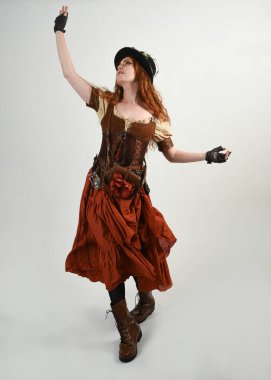 Uzun, yürüyen Steampunk Botanikçisi, çılgın bilim adamı, silindir şapkalı ve gözlüklü kadın model. Kızıl Saçlı Fantezi Karakteri Beyaz Stüdyo Arkaplanında Pozisyon