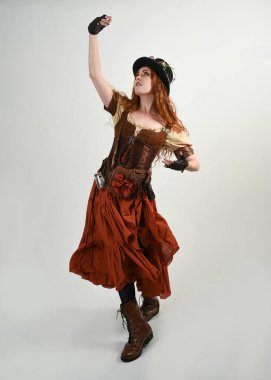 Uzun, yürüyen Steampunk Botanikçisi, çılgın bilim adamı, silindir şapkalı ve gözlüklü kadın model. Kızıl Saçlı Fantezi Karakteri Beyaz Stüdyo Arkaplanında Pozisyon