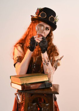 Steampunk Botanikçisi, çılgın bilim adamı, silindir şapkalı ve gözlüklü kadın model. Kızıl Saçlı Fantezi Karakteri Beyaz Stüdyo Arkaplanında Pozisyon