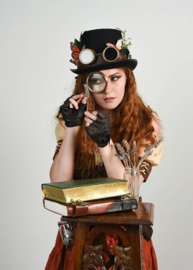 Steampunk Botanikçisi, çılgın bilim adamı, silindir şapkalı ve gözlüklü kadın model. Kızıl Saçlı Fantezi Karakteri Beyaz Stüdyo Arkaplanında Pozisyon