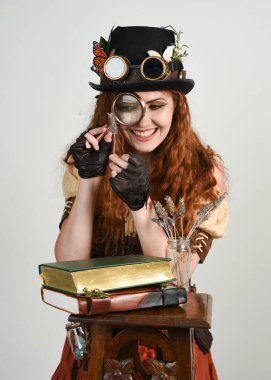 Steampunk Botanikçisi, çılgın bilim adamı, silindir şapkalı ve gözlüklü kadın model. Kızıl Saçlı Fantezi Karakteri Beyaz Stüdyo Arkaplanında Pozisyon