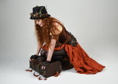 Steampunk Botanikçisi, deli bilim adamı, silindir şapkalı ve gözlüklü kadın model. Kızıl Saçlı Fantezi Karakteri Beyaz Stüdyo Arkaplanda Kelebeklerle Poz Veriyor