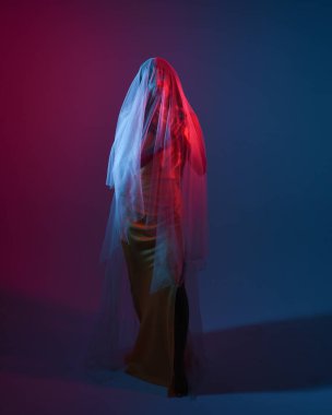 Saf kefen örtüsüne sarılı bir kadın modelin portreleri, canlı neon pembe ve mavi ışıkla aydınlatılıyor, karamsar, rüya gibi ve görsel olarak çarpıcı seriler yaratıyor, ruhani ışıkla kalın rengi harmanlıyor..