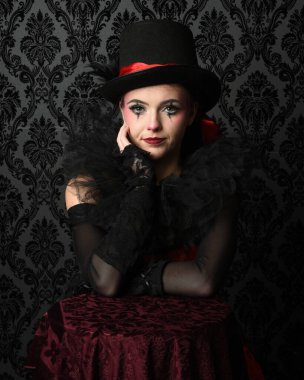 Silindir şapka ve gotik eldivenler takan sirk burlesk modelinin göz kamaştırıcı portresi, tiyatro pozu. koyu fantezi yatak odası eski duvar kağıdı arka planı.