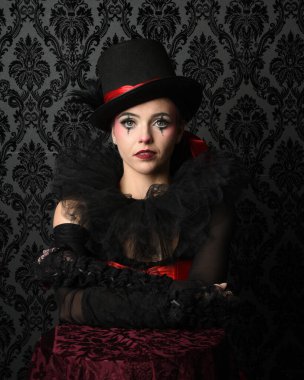 Silindir şapka ve gotik eldivenler takan sirk burlesk modelinin göz kamaştırıcı portresi, tiyatro pozu. koyu fantezi yatak odası eski duvar kağıdı arka planı.