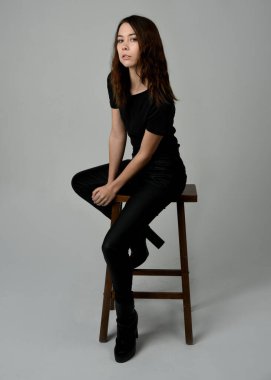 Siyah tişörtlü Esmer Kadın Yüksek Sandalye Stüdyosunun Yan Tarafında Beyaz Arkaplanda Oturan Modern Moda Pozu