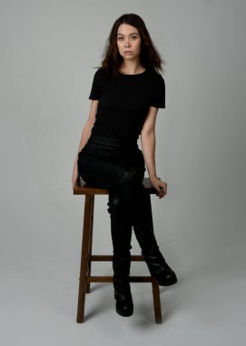 Siyah tişörtlü Esmer Kadın Yüksek Sandalye Stüdyosunun Yan Tarafında Beyaz Arkaplanda Oturan Modern Moda Pozu