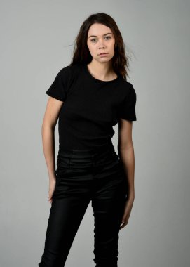 Siyah gömlekli ve deri pantolonlu güzel esmer kız model, stüdyo arka planında izole edilmiş yakın plan portresi. güçlü kendinden emin duruş.