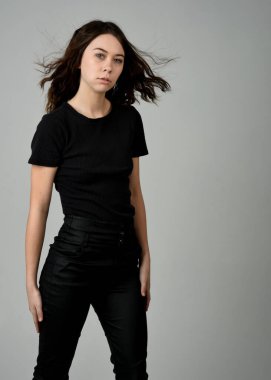 Siyah gömlekli ve deri pantolonlu güzel esmer kız model, stüdyo arka planında izole edilmiş yakın plan portresi. güçlü kendinden emin duruş.