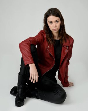 Kırmızı Deri Ceketli Esmer Kadın Diz çöküp Tam Uzunlukta Oturan Stüdyo Portresi Beyaz Arka planda İzole Edilen Modern Distopya Moda