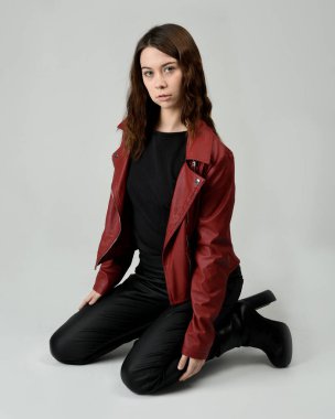 Kırmızı Deri Ceketli Esmer Kadın Diz çöküp Tam Uzunlukta Oturan Stüdyo Portresi Beyaz Arka planda İzole Edilen Modern Distopya Moda