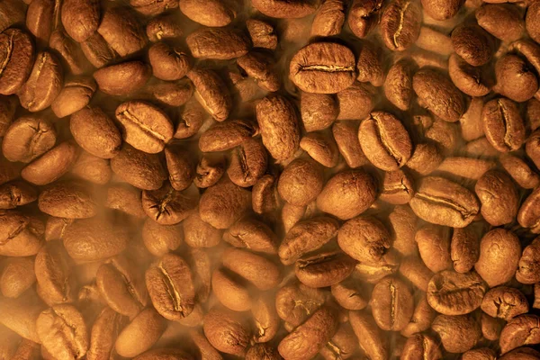 Roasted coffee ready to be brewed, texture of coffee beans, warm light and coffee and copy space.