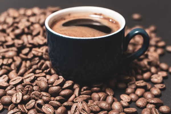 近くに豆が散乱したコーヒーカップ ホットコーヒーからの軽い蒸気 — ストック写真