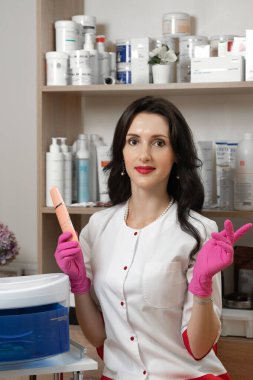 Bir kozmetik uzmanının portresi bakteriyel bir kutunun yanında, elinde yüz temizleyicisi tutan bir güzellik uzmanı..