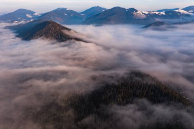 Karpatlar 'ın zirveleri sabah bulutların arasında, tepede, dron tarafından çekilen güneş ağları sabah bulutların arasında..