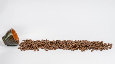 Kahve çekirdekleri fincandan dökülür, kahve izole edilmiş beyaz arka planda, metin için kopyalama alanı.