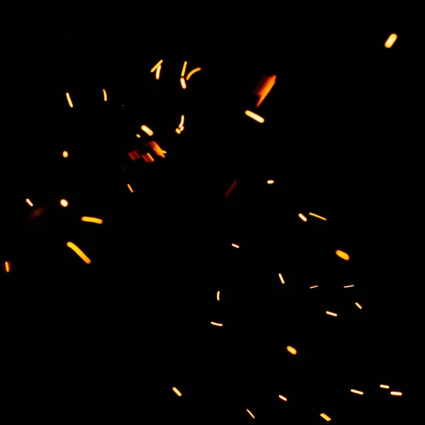 黒い背景の上に明るい火花 暗い背景の上に黄色のホットぼやけた光 夜空に隔離された燃え上がるメンバーの粒子が飛んで輝きます — ストック写真