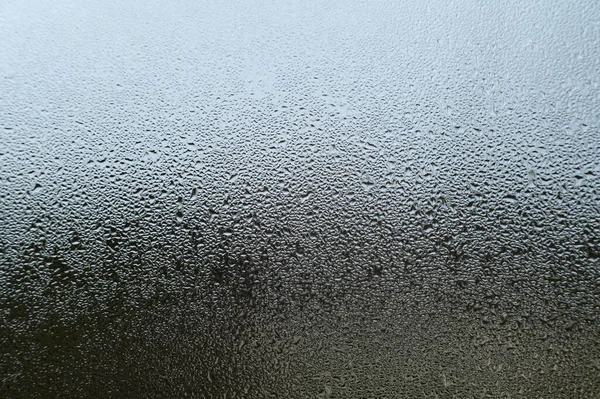 Dew drops and condensation on glass, cold season and high humidity on windows in houses, condensation texture with water drops.