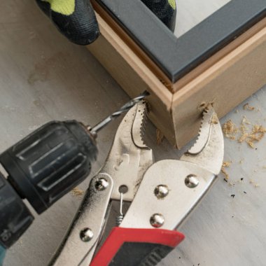 Zanaatkar köşedeki bağlantı için kapıyı deliyor, pense iki kapı levyesini tutuyor, kapı takılı..