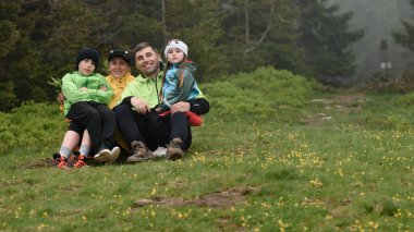 Vorokhta, Ukrayna 12 Haziran 2022: Parlak elbiseli turistler Karpatlar 'da dinleniyor, bir aile dağın tepesindeki çimlerin üzerinde oturuyor.