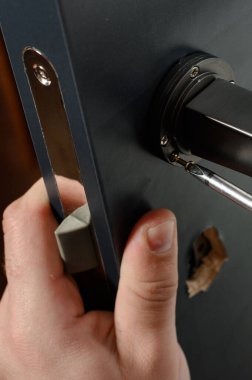 A man installs a door handle in a door, carpentry work at home, repair and restoration work.