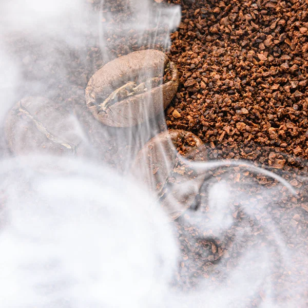 Black coffee beans with light smoke from steam, texture of coffee beans, copy space and place for writing.