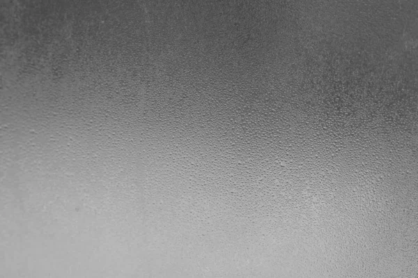 Glass and condensation on it, cooling outside and consequences in poorly heated houses, texture of condensation on the window.