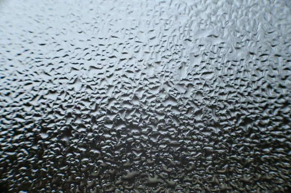 large drops of dew on the window after condensation on the window, texture of water drops on the glass.