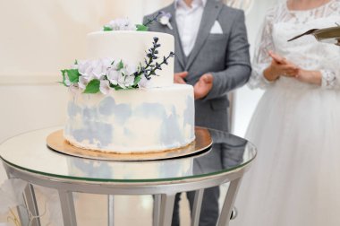 Bir gelin ve damat kutlama pastalarının yanında duruyor, pastayı yakın..