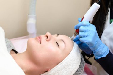 A cosmetologist performs a mesotherapy rejuvenation procedure with the help of dermapen, a visit to a cosmetologist.