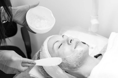 The process of applying a moisturizing mask to the face in a spa salon, applying the mask with a spatula.