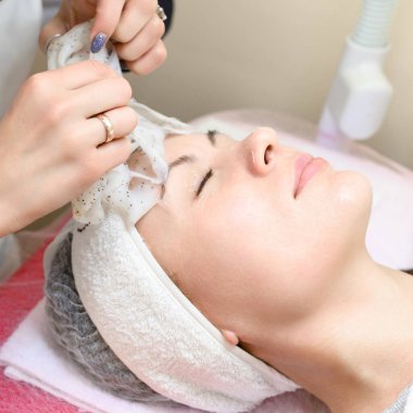 Removing a moisturizing mask from the face in a cosmetology office, cosmetology procedures in a spa salon.