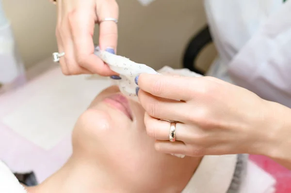 Removing a moisturizing mask from the face in a cosmetology office, cosmetology procedures in a spa salon.