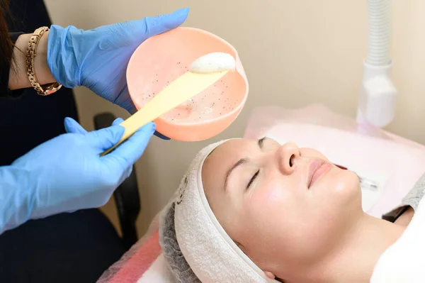 The process of applying a moisturizing mask to the face in a spa salon, applying the mask with a spatula.