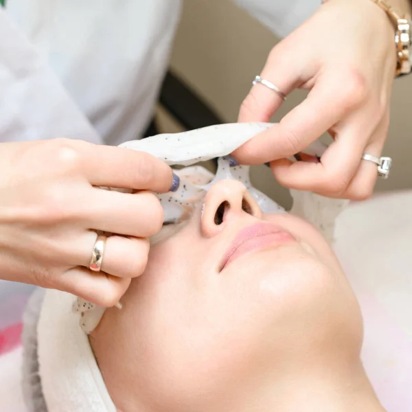 Removing a moisturizing mask from the face in a cosmetology office, cosmetology procedures in a spa salon.